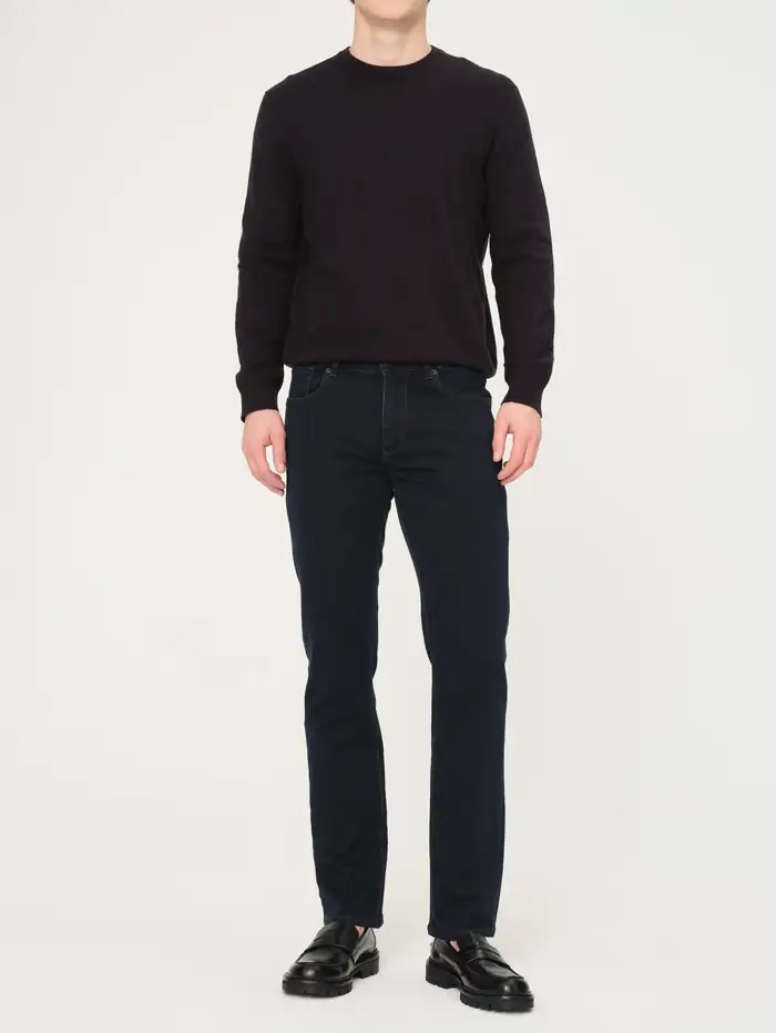Model wearing a black crewneck sweater and dark denim