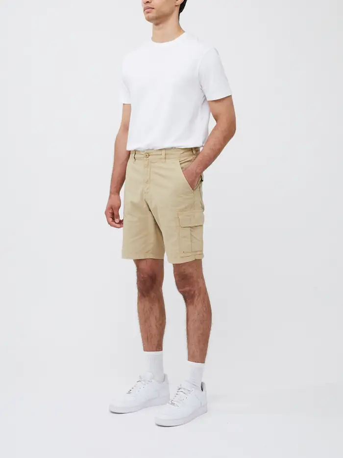 Model wearing tan shorts and a white t-shirt